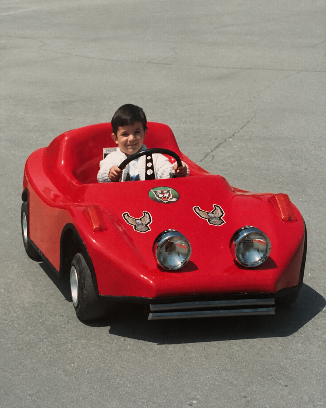 Editorial treatment of Vlad Tenev's childhood photograph in a red ride-on car